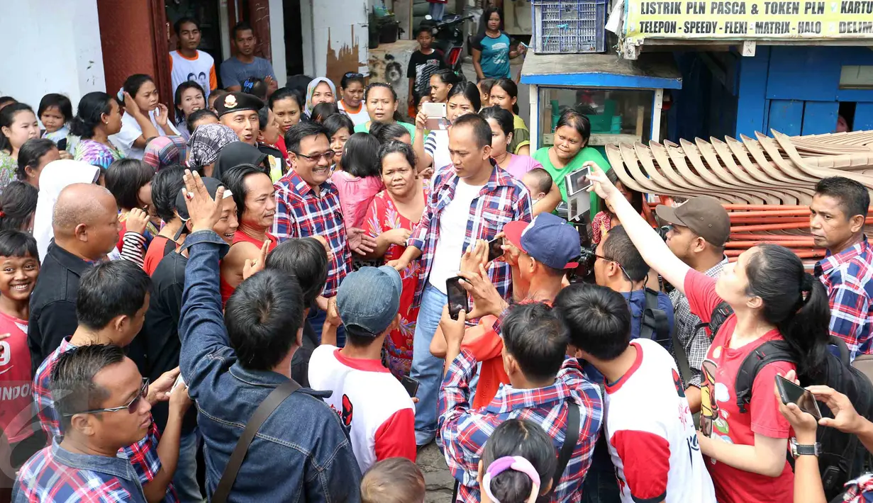 Warga Jelambar Timur mengambil gambar Cawagub DKI Jakarta, Djarot Saiful Hidayat saat blusukan ke Jelambar, Jakarta, Jumat (6/1). Dalam blusukannya Djarot meminta kepada warga agar tidak termakan oleh isu yang menimbulkan keresahan. (Liputan6.com)