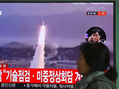 Seorang wanita melewati layar televisi yang menyiarkan berita peluncuran rudal oleh Korea Utara (Korut), di sebuah stasiun kereta di Seoul, Korea Selatan, Selasa (5/4). Rudal itu ditembakkan dari wilayah timur Korut ke arah Laut Jepang. (JUNG Yeon-Je/AFP)