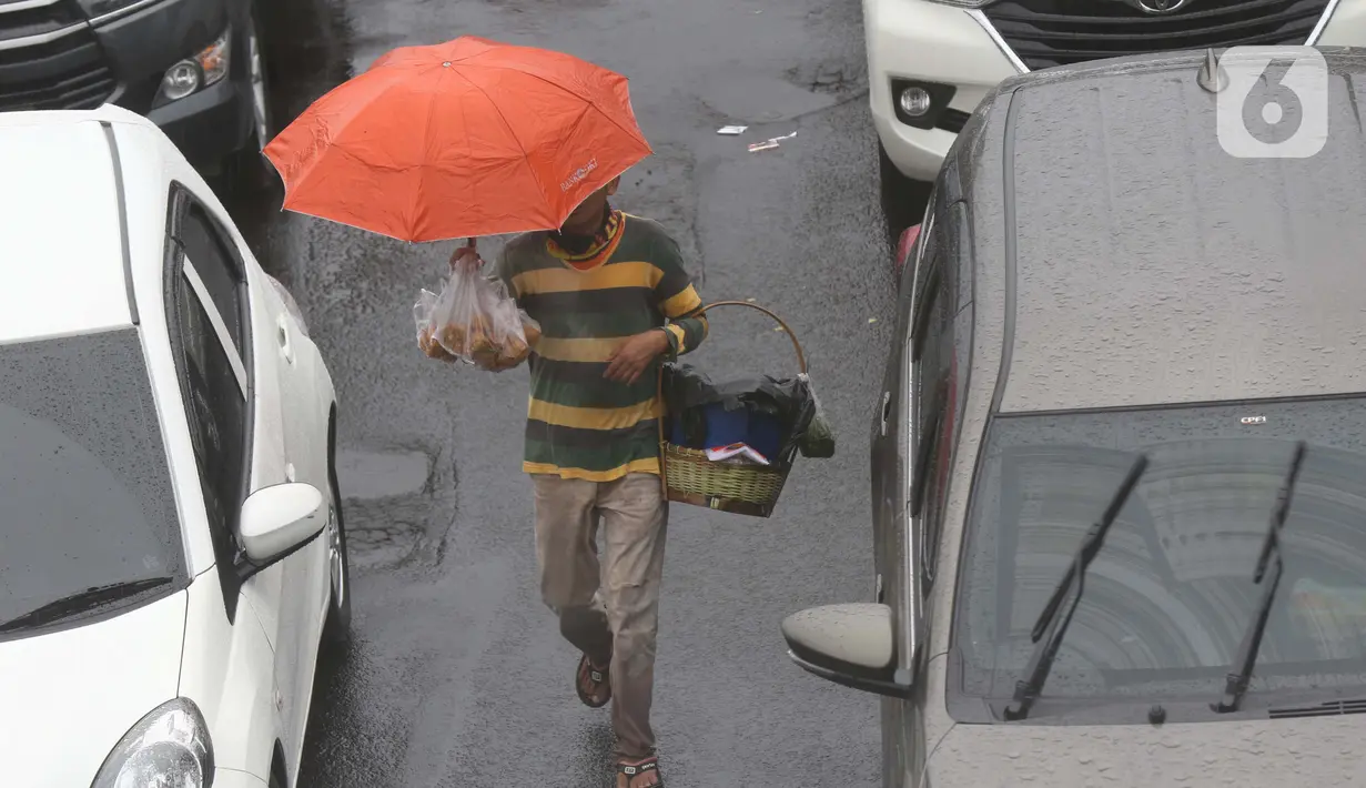 Seorang pedagang asongan menawarkan dagangan kepada pengendara di jalan tol Jagorawi yang sedang menanti waktu buka tutup jalur menuju kawasan wisata puncak, Bogor, Jawa Barat, Sabtu (31/10/2020). (Liputan6.com/Helmi Fithriansyah)