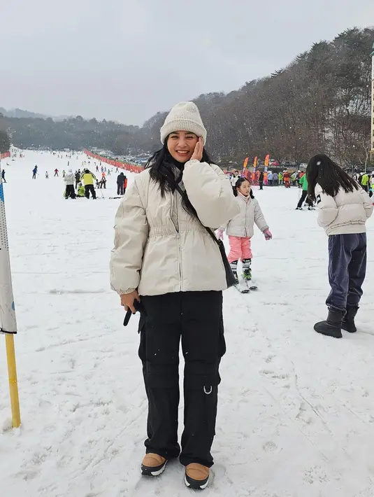 Bermain di salju, Hesti Purwadinata mengenakan puffer jacket putih, yang serasi dengan beanienya. Penampilannya semakin sempurna dengan cargo pants berwarna hitam. [Foto: Instagram/hestipurwadinata]