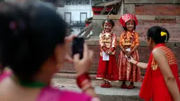 Dua anak perempuan Nepal tersenyum saat foto bersama saat acara tradisi Kumari di Hanuman Dhoka, Kathmandu, Nepal, Senin (4/9). Anak perempuan di bawah usia 9 tahun dianggap sebagai wujud nyata dari Dewi yang “hidup”. (AP Photo/Niranjan Shrestha)