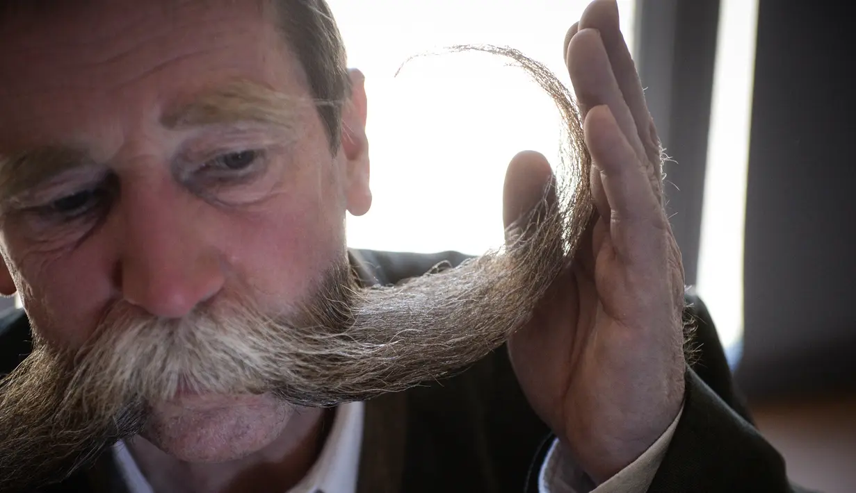 Peserta merapikan janggutnya sebelum mengikuti kompetisi janggut dan kumis di Ecomusee d'Alsace, Ungersheim, Prancis, 30 Maret 2017. Di acara itu, peserta saling berlomba menampilkan kumis dan janggut dengan tatanan yang paling unik. (SEBASTIEN BOZON/AFP)