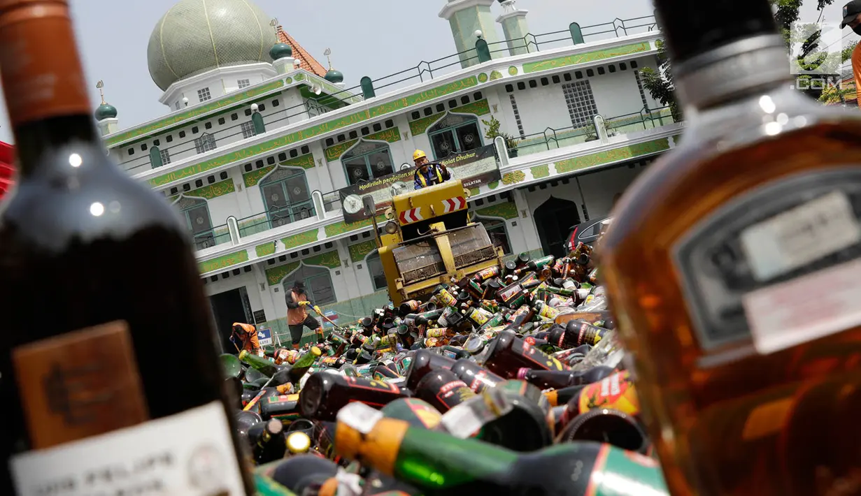 Petugas menggiling ribuan botol minuman keras (miras) menggunakan alat berat saat pemusnahan di halaman Mapolres Jakarta Selatan, Selasa (23/5). Ada 9.279 botol senilai Rp588 juta yang dimusnahkan dalam kegiatan ini. (Liputan6.com/Immanuel Antonius)