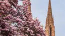 Orang-orang bersantai di bawah pohon magnolia yang sedang mekar di tepi Sungai Ill, Strasbourg, Prancis, 21 Maret 2022. Magnolia adalah salah satu marga tumbuhan berbunga yang dikenal luas karena bunganya indah dan menyebarkan aroma harum. (PATRICK HERTZOG/AFP)