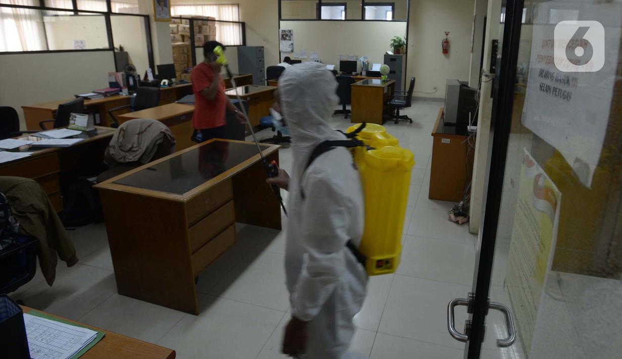 Petugas menyemprotkan cairan disinfektan di ruang kerja dan ruang pelayanan Suku Dinas Sosial Jakarta Timur, Jumat (18/2/2022). Sebanyak 6 orang yang terpapar Covid-19 sedang menjalani isolasi di rumah, sementara pelayanan ditutup selama tiga hari. (merdeka.com/Imam Buhori)