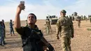 Seorang anggota pasukan Irak berselfie sebelum menembakkan mortir ke arah militan ISIS di Qayyarah, selatan Mosul, (21/10). (AFP PHOTO/Bulent KILIC)