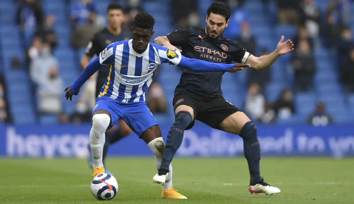 Gelandang Manchester City, Ilkay Gundogan berebut bola dengan gelandang Brighton and Hove Albion, Yves Bissouma pada pekan 37 Liga Inggris di Amex Stadium, Rabu (19/5/2021) dinihari WIB. Manchester City menyerah di markas Brighton dengan skor 2-3. (Mike Hewitt, Pool via AP)