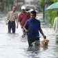 Seorang warga bersama anjingnya melewati banjir di Colombo, Senin (16/5). Pejabat pemerintah terkait juga memerintahkan untuk membangun kanal guna mengendalikan banjir serta menanggulangi tanah longsor terulang lagi. (Lakruwan Wanniarachchi/AFP)