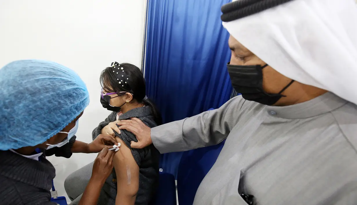 Seorang anak perempuan menerima dosis vaksin covid-19 Pfizer-BioNTech di pusat vaksinasi di Kuwait International Fairground di Kuwait City pada 3 Februari 2022. Kementerian kesehatan Kuwait mulai memvaksinasi anak usia 5 hingga 11 tahun. (YASSER AL-ZAYYAT / AFP)