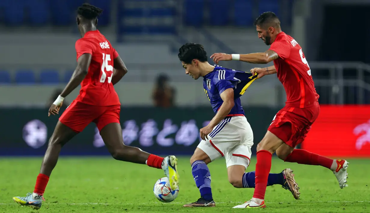 Pemain Kanada Steven Vitoria menarik pemain Jepang Ayase Ueda pada pertandingan persahabatan di Dubai, 17 November 2022. Kanada mengalahkan Jepang dengan skor 2-1. (AP Photo/Christopher Pike)