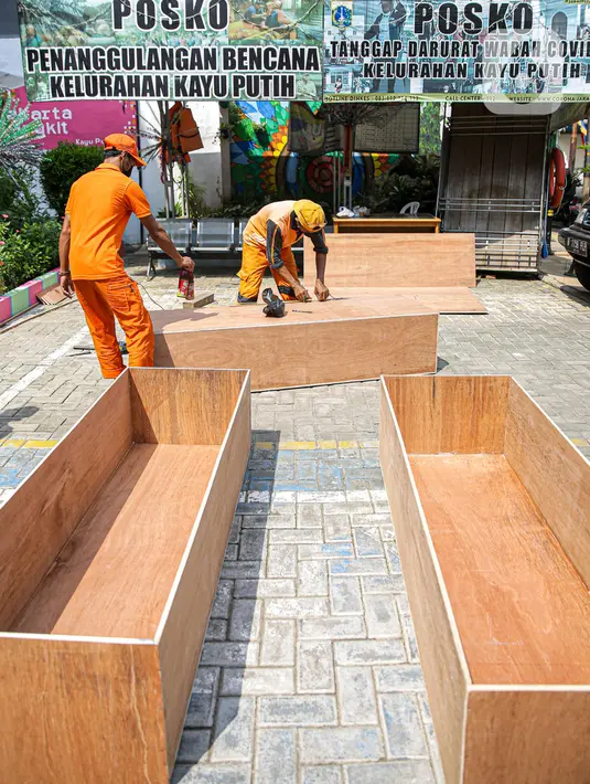Petugas PPSU menyelesaikan pembuatan peti jenazah di Kantor Kelurahan Kayu Putih, Jakarta, Selasa, (6/7/2021). Kelurahan Kayu Putih berinisiatif membuat peti jenazah dilatar belakangi warganya yang terkendala ketersediaan peti saat angka kematian COVID-19 meningkat. (Liputan6.com/Faizal Fanani)
