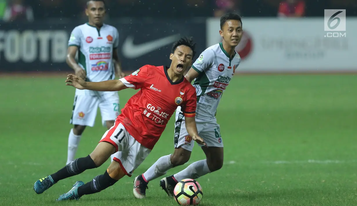 Penyerang Persija, Novri Setiawan (tengah) terjatuh saat berebut bola dengan pemain PS TNI, Roni Sugeng Ariyanto pada lanjutan Liga 1 Indonesia di Stadion Patriot Candrabhaga, Bekasi, Sabtu (30/9). Persija menang 4-1. (Liputan6.com/Helmi Fithriansyah)