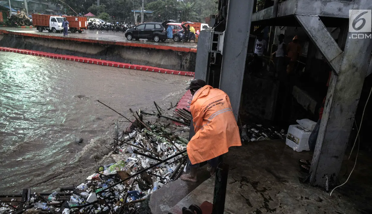 Petugas membersihkan sampah yang menyangkut di Pintu Air Manggarai, Jakarta, Senin (5/2). Hal itu dilakukan agar tumpukan sampah tidak menutupi arus air. (Liputan6.com/Faizal Fanani)