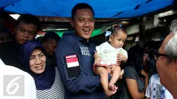 Calon Gubernur DKI Jakarta Agus Harimurti Yudhoyono menggendong seorang balita saat mengunjungi Pasar Paseban Jakarta Pusat, Jumat (11/11). Agus disambut hangat pedagang maupun pengunjung pasar tersebut. (Liputan6.com/Gempur M Surya)
