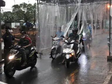 Pengendara sepeda motor keluar dari bilik penyemprotan disinfektan di pintu masuk Perumahan Tamansari Persada Raya, Jatibening, Bekasi, Jawa Barat, Selasa (31/3/2020). Bilik disinfektan dipasang untuk mencegah penyebaran virus corona COVID-19 di area kompleks. (Iqbal S. Nugroho)