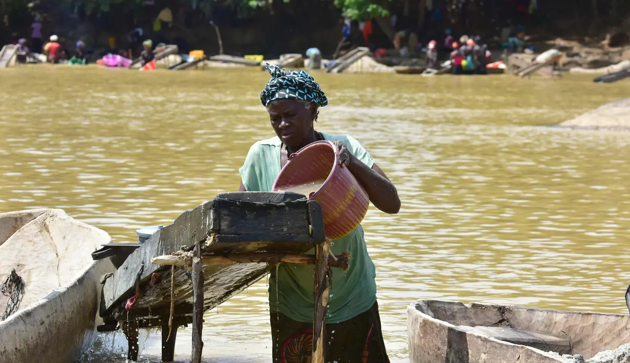 Seorang penembang emas wanita menyaring kerikil dan memisahkan bintik-bintik emas dari lumpur di sungai Pampana di dekat Mekeni, sebelah utara Sierra Leone (5/3). (AFP Photo/Issouf Sanogo)