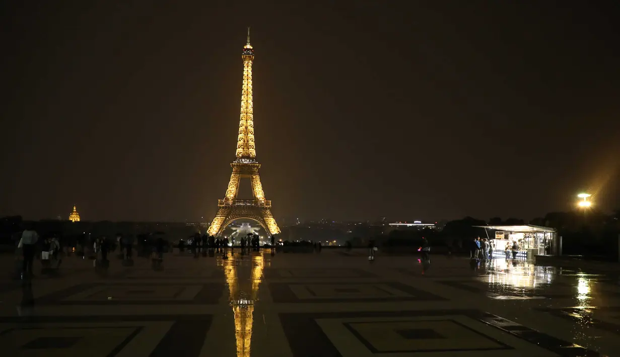 Sejumlah wisatawan menikmati pemandangan Menara Eiffel yang diterangi lampu dari Trocadero Plaza di Paris, Prancis (1/9).( AFP Photo/Ludovic Marin)