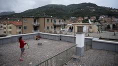 Carola Pessina bermain tenis dengan Vittoria Oliveri di atas atap rumah mereka selama lockdown COVID-19 di Finale Ligure, Wilayah Liguria, Italia (19/4/2020). Setiap hari Carola, 11, dan Vittoria, 13, bermain tenis dari satu atap ke atap lain di rumah mereka untuk berlatih. (AFP/Marco Bertorello)