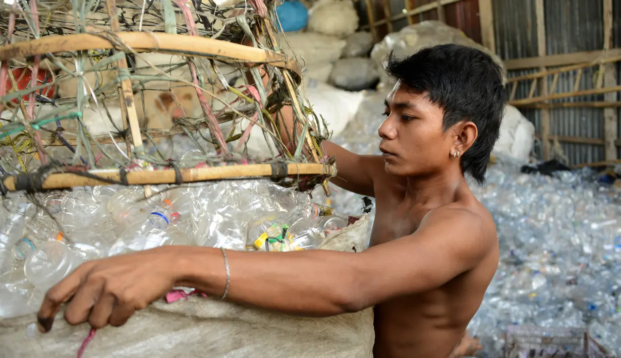 Pengumpul sampah memasukan botol plastik ke dalam karung di sebuah gudang sampah di Nusa Dua, di pulau resor Indonesia Bali (2/5). (AFP Photo/Sonny Tumbelaka)