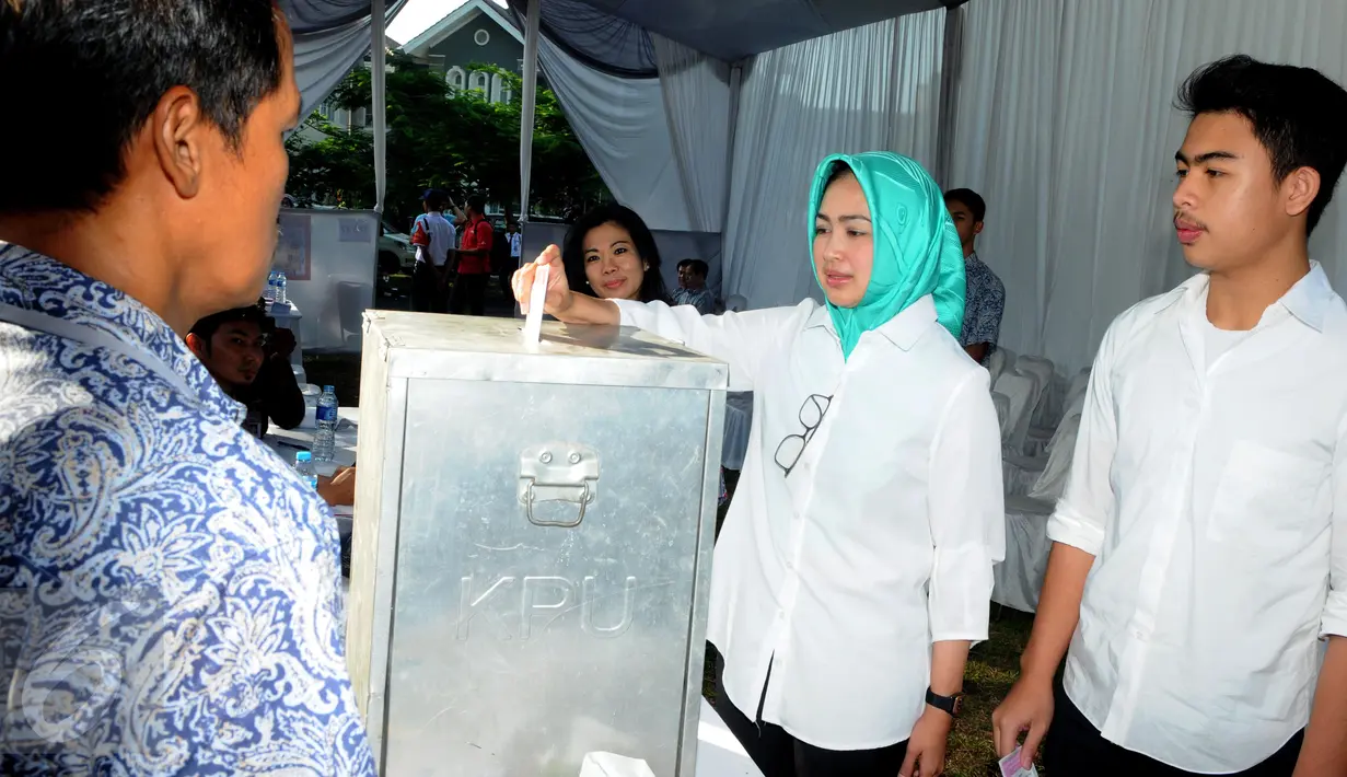 Calon Walikota Tangerang Selatan, Airin Rachmi Diany (kiri) bersama putra pertama, TB Ghifari Wardana memasukkan surat suara ke kotak suara di TPS 17 Serpong Utara, Tangerang Selatan, Banten, Rabu (9/12). (Liputan6.com/Helmi Afandi)