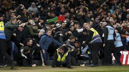 Sejumlah petugas keamanan berusaha menghalangi suporter yang akan masuk ke lapangan setelah gol ketiga Manchester United yang dicetak oleh Bruno Fernandes ke gawang Nottingham Forrest. Namun satu orang suporter pria berkacamata (kiri) berhasil lolos dari jangkauan petugas. (AP/PA/Tim Goode)