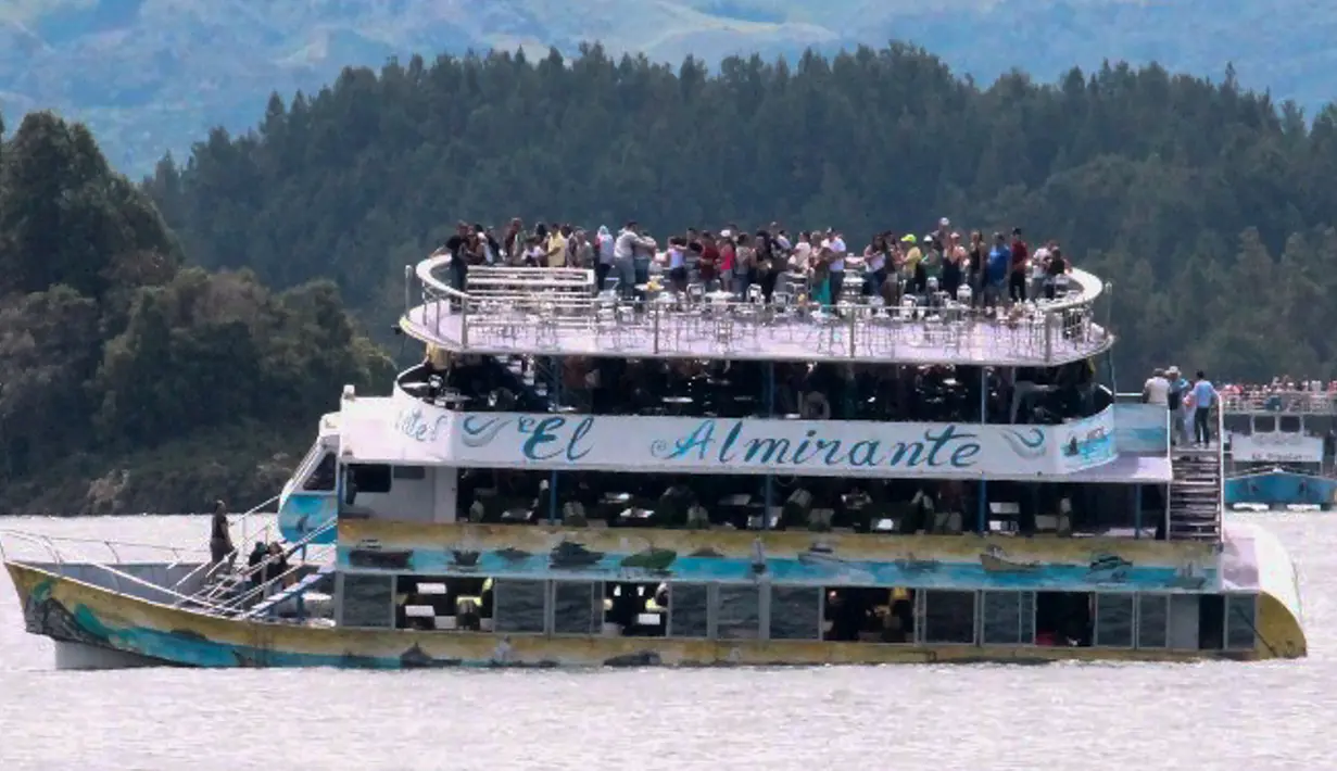 Penumpang terlihat berada di atas kapal wisata Almirante sesaat sebelum tenggelam di sebuah waduk di Kolombia barat daya, Minggu (25/6). Sedikitnya sembilan orang meninggal dunia dan 28 lainnya hilang dalam peristiwa itu. (Juan QUIROZ/AFPP)