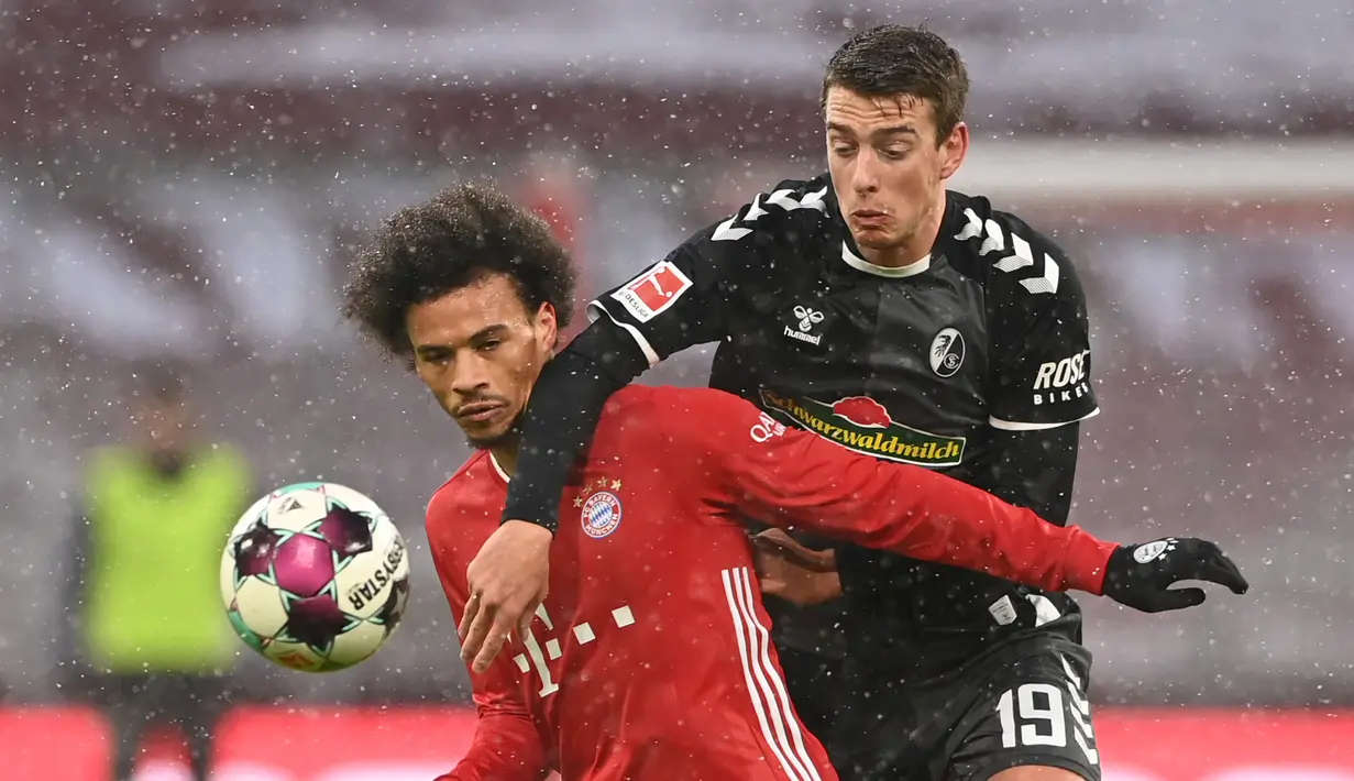 Gelandang Bayern Munich, Leroy Sane (kiri) berebut bola dengan striker Freiburg, Janik Haberer dalam laga lanjutan Liga Jerman 2020/21 pekan ke-16 di Allianz Arena, Minggu (17/1/2021). Bayern Munich menang 2-1 atas Freiburg. (AFP/Christof Stache/Pool)