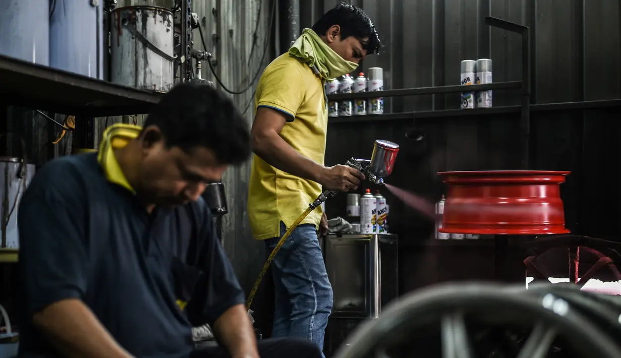 Pekerja membersihkan dan menyemprotkan pelek di sebuah bengkel di Ampang, di pinggiran kota Kuala Lumpur, Malaysia (18/7). (AFP Photo/Mohd Rasfan)