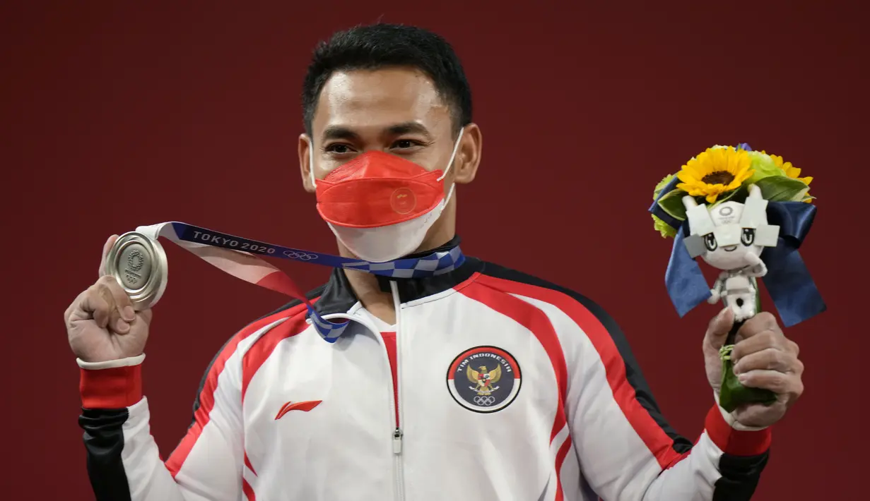 Lifter andalan Indonesia, Eko Yuli Irawan menunjukkan medali perak Olimpiade Tokyo 2020 cabang angkat besi kelas 61kg putra di Tokyo International Forum, Minggu (25/7/2021). Eko Yuli meraih medali perak dengan total angkatan 302 kg. (AP Photo/Luca Bruno)