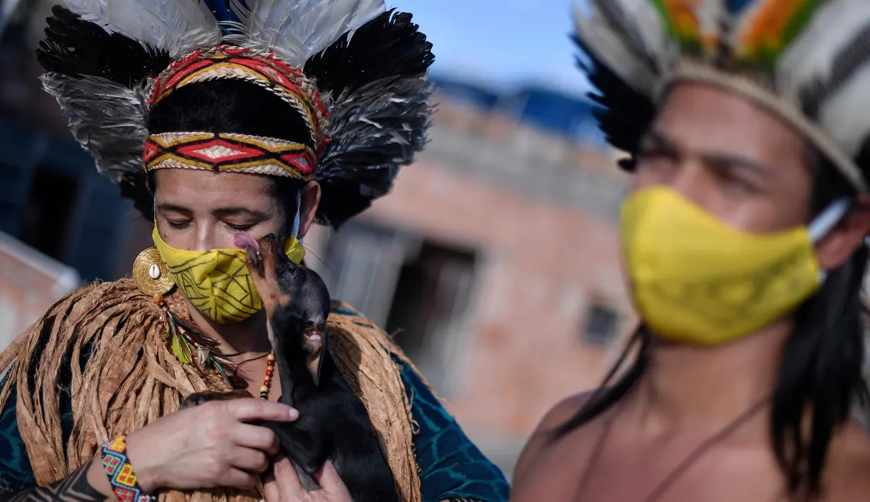 Angoho (kiri) dan suaminya, Hayo mengenakan masker di tengah Pandemi coronavirus novel COVID-19 di Vila Vitoria favela di pinggiran Belo Horizonte, negara bagian Minas Gerais, Brasil (8/7/2020). Angoho dan saudara-saudaranya telah diusir dua kali dari tanah mereka. (AFP/Douglas Magno)