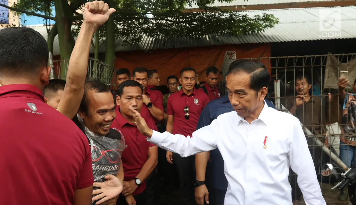 Presiden Joko Widodo atau Jokowi melihat ke arah warga yang antusias menyambut kedatangannya di Pasar Minggu, Jakarta, Jumat (22/2). Jokowi harus meladeni permintaan salam dan foto dari pedagang dan warga. (Liputan6.com/Angga Yuniar)
