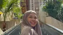 Pada foto lain, ia terlihat mengenakan busana taupe dengan latar arsitektur kota. Warna netral ini memberi kesan modern dan dewasa namun tetap lembut. Senyum lebarnya membuat penampilan terasa lebih hidup dan natural, menunjukkan momen bahagia selama perjalanan ibadah.  [@rklopper].