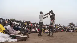 Seorang penonton menawarkan tip uang tunai kepada pegulat saat kompetisi gulat tradisional Nuba antara tim dari daerah Haj Youssef dan Omdurman di Ibu Kota Khartoum, Sudan, 30 Juli 2021. (Abdulmonam EASSA/AFP)