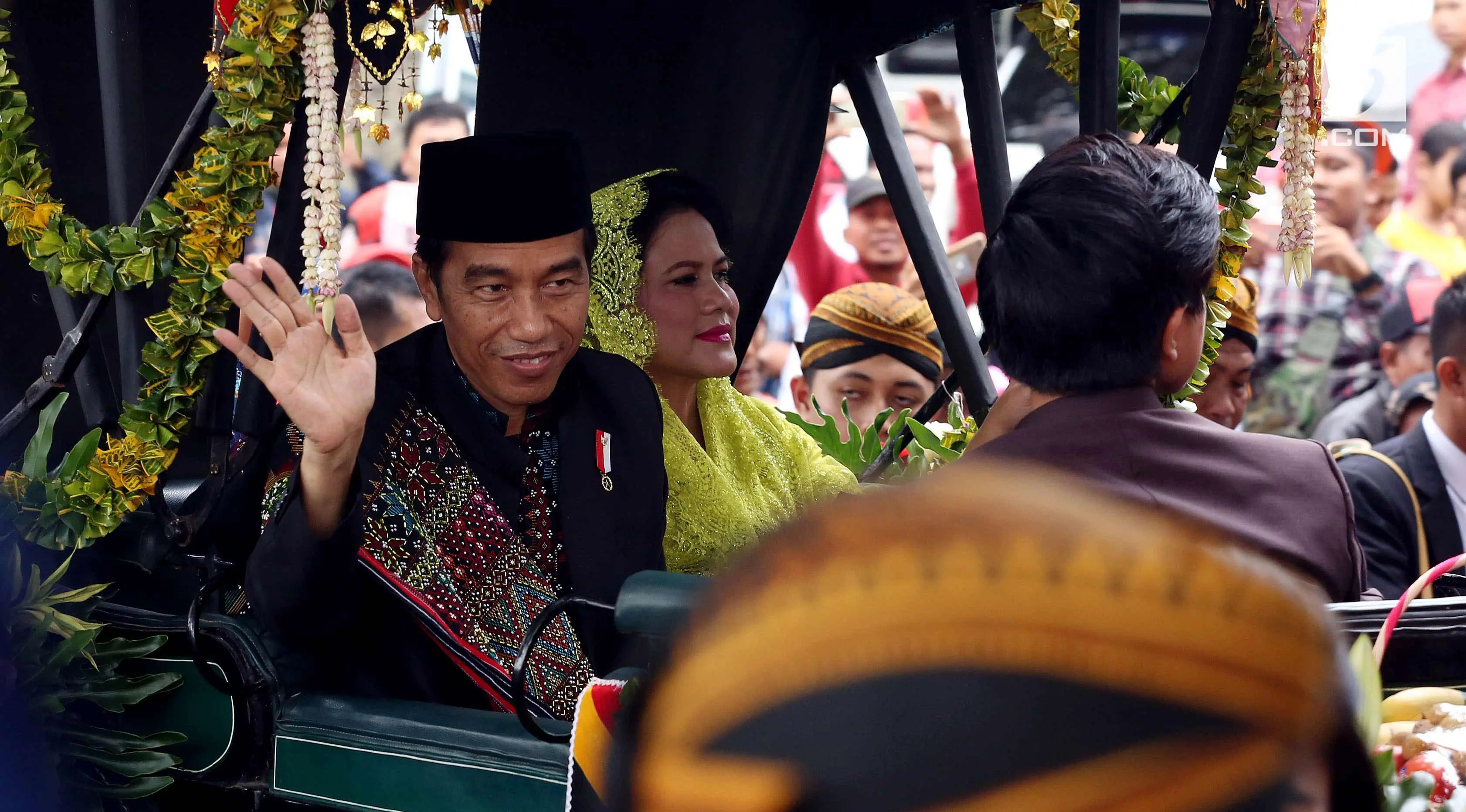 Presiden Joko Widodo bersama Ibu Negara Iriana menyapa warga saat kirab resepsi pernikahan Kahiyang Ayu-Bobby Nasution di Kota Medan, Sumatera Utara, Minggu (26/11). (Liputan6.com/Johan Tallo)