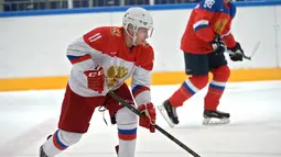 Presiden Rusia, Vladimir Putin mengejar bola pada sesi latihan hoki es disaat perayaan natal umat kristen ortodoks di arena Galaktika, Sochi, Rabu (6/1/2016). (Aleksey NIKOLSKYI/Sputnik/AFP)