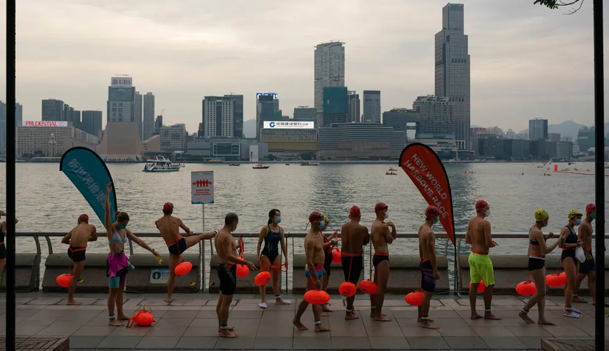 Para perenang menunggu di garis start jelang lomba renang tahunan di Pelabuhan Victoria, Hong Kong, Minggu (23/10/2022). Lomba renang tahunan melintasi Pelabuhan Victoria ini kembali diadakan setelah tiga tahun ditiadakan karena protes pro-demokrasi dan pandemi COVID-19. (AP Photo/Anthony Kwan)
