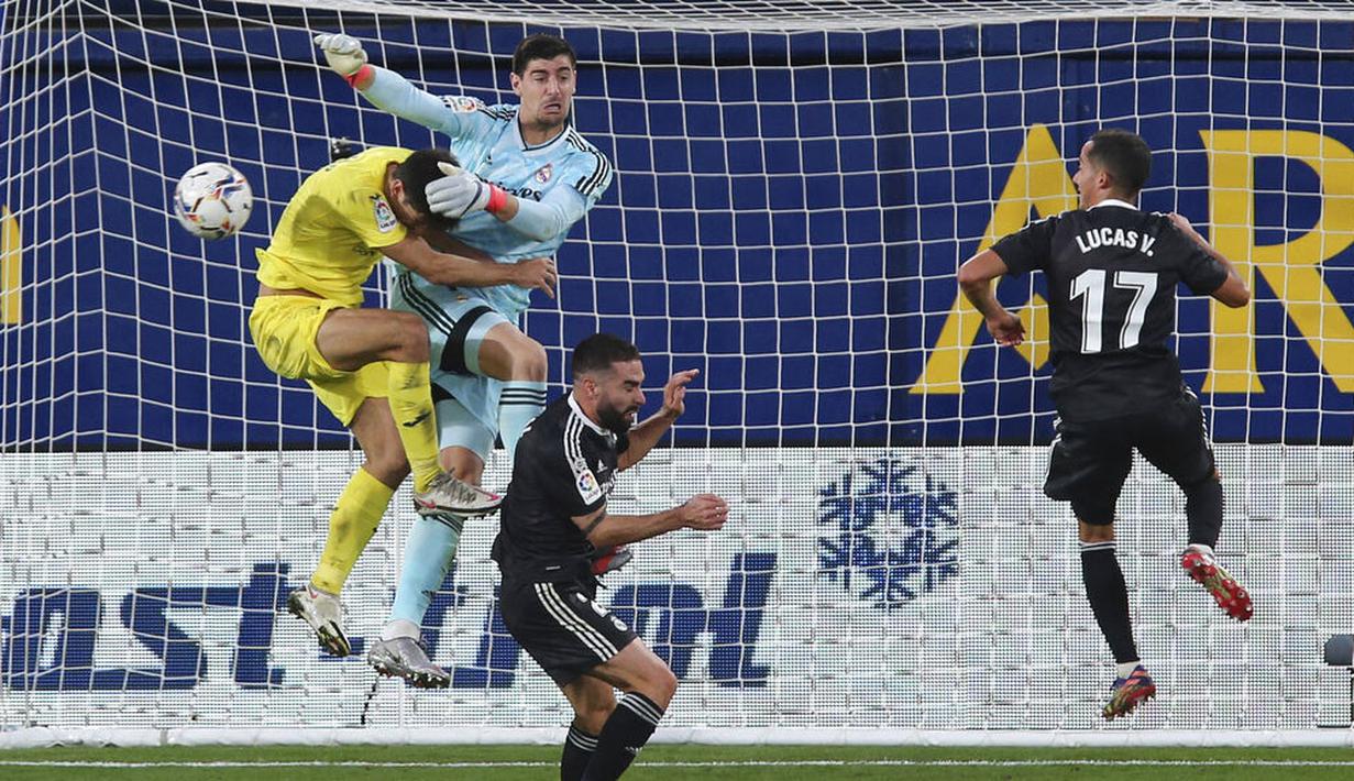 Kiper Real Madrid, Thibaut Courtois, berebut bola dengan pemain Villarreal, Gerard Moreno, pada laga Liga Spanyol di Stadion Ceramica, Minggu (22/11/2020). Kedua tim bermain imbang 1-1. (AP/Alberto Saiz)