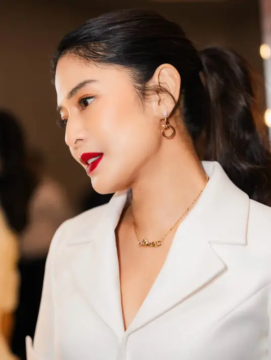Penampilannya tampak mewah dengan set perhiasan emas dari Cartier, dari anting-anting model lingkaran serasi dengan liontin kalungnya.  [@therealdisastr]