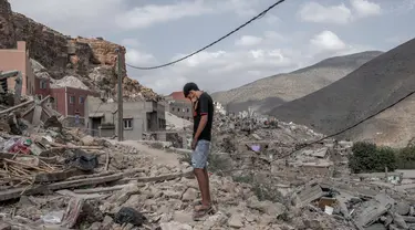 Seorang pemuda berdiri di atas reruntuhan rumah yang hancur di tengah operasi penyelamatan yang sedang berlangsung di desa Imi N'Tala, dekat Amizmiz, pada tanggal 12 September 2023. (BULENT KILIC/AFP)