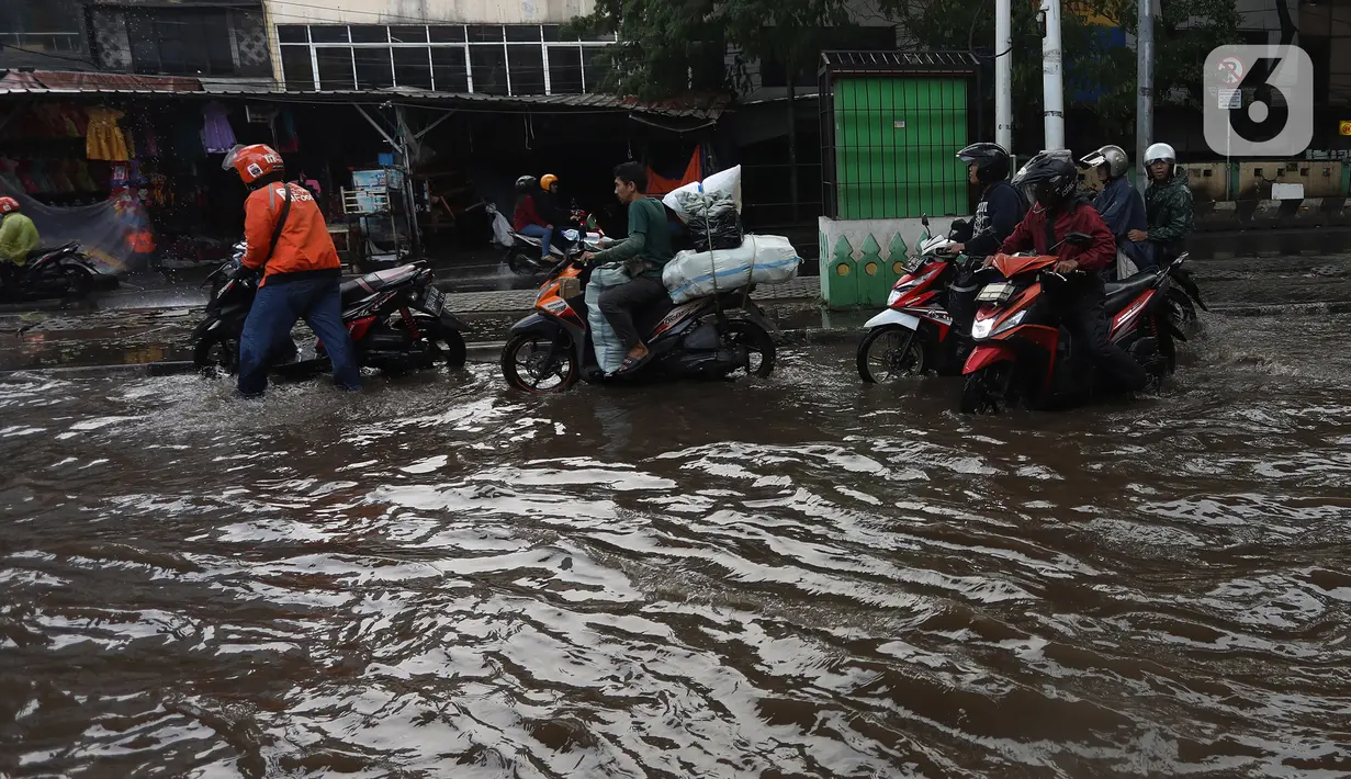 Banyak pesepeda motor menuntun kendaraannya untuk menerobos genangan. (Liputan6.com/Johan Tallo)