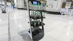 Sebuah gambar pada 15 Juni 2021 menunjukkan robot pembawa air Zamzam yang digunakan pertama kalinya di sekitar Masjidil Haram di Makkah, Arab Saudi. Robot itu masing-masing dilengkapi tiga rak berisi air zamzam botolan sehingga para jemaah bisa mengambil sendiri tanpa kontak langsung. (AFP Photo)