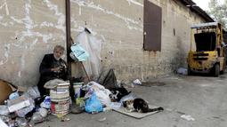 Georges Gerges, yang dijuluki "Kapten" memberi makan kucingnya di sudut jalan kawasan industri Dora di pinggiran utara Beirut, Rabu (8/11). Kakek 90 tahun itu kehilangan sebagian besar hartanya selama perang saudara yang melanda Lebanon. (JOSEPH EID/AFP)