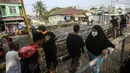 Warga beraktivitas melewati area sekitar proyek revitalisasi Jembatan Cibubur, Jakarta, Selasa (2/8/2022). Revitalisasi dilakukan untuk mengantisipasi risiko banjir akibat rendahnya muka jembatan serta risiko kecelakaan akibat tidak adanya trotoar. (Liputan6.com/Faizal Fanani)