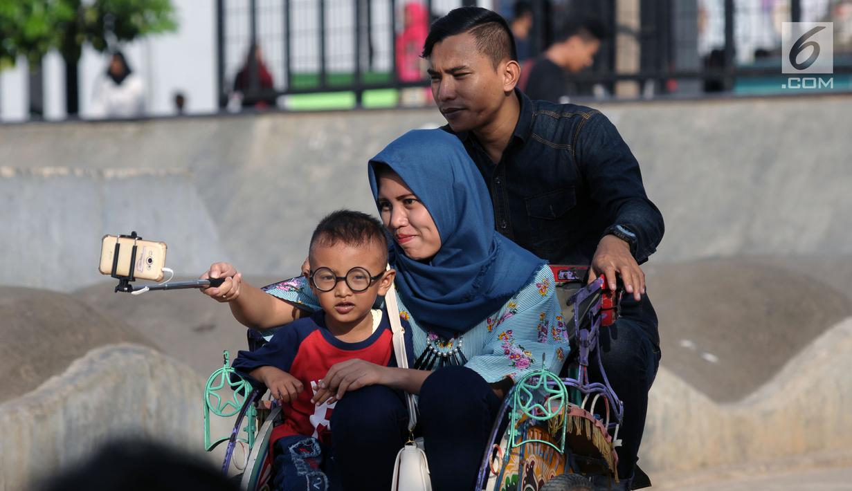 Salah satu keluarga berswafoto bersama di area RTH Kalijodo, Rabu (20/6). Banyaknya pilihan permainan buat anak-anak menjadikan RTH Kalijodo memiliki daya tersendiri untuk menghabiskan waktu libur bersama keluarga. (Lipiutan6.com/Helmi Fithriansyah)