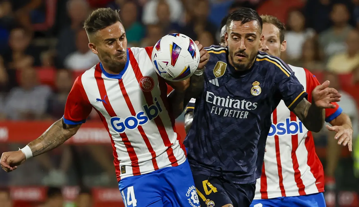 Striker Real Madrid, Joselu (kanan) berebut bola dengan gelandang Girona, Aleix Garcia pada laga pekan ke-8 Liga Spanyol 2023/2024 di Montilivi Stadium, Girona, Spanyol, Sabtu (30/9/2023) malam WIB. (AP Photo/Joan Monfort)