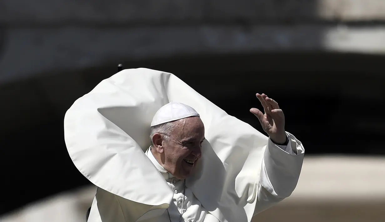 Angin kencang menerpa jubah Paus Fransiskus saat memberkati umat setelah misa pada pertemuan dengan para pemuda di Lapangan Santo Petrus, Vatikan, Minggu (12/8). Tiupan angin tersebut membuat wajah Paus tertutup jubah. (AFP PHOTO / FILIPPO MONTEFORTE)