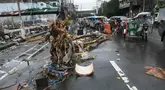 Pengendara kendaraan bermotor melewati batang pohon yang tergeletak di salah satu jalan di Manila, Filipina pada 25 Juli 2024. (TED ALJIBE/AFP)