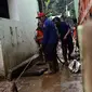 Petugas Damkar PB membersihkan lumpur sisa banjir di salah satu gang di kawasan Rawajati, Jakarta, Sabtu (27/4). Banjir akibat luapan air sungai Ciliwung sempat melanda kawasan ini pada Jumat (26/4). (Liputan6.com/Helmi Fithriansyah)