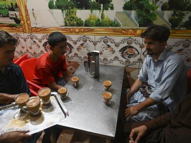 Pramusaji menyajikan cangkir teh kepada pelanggan di sebuah restoran di Islamabad, Pakistan, Rabu (15/6/2022). Menteri Perencanaan Pakistan Ahsan Iqbal yang baru terpilih menghadapi kritik, menyusul permohonannya kepada warga untuk mengurangi minum teh guna membantu menghemat impor di tengah krisis ekonomi yang semakin dalam. (Aamir QURESHI / AFP)