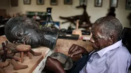 Edward Njenga bekerja memperbaiki patung karyanya yang berjuluk 'Women's Guild Member (2008)' di bengkelnya, Nairobi, Kenya, Senin (12/3).  Njenga lahir pada tahun 1922 dan menjadi pematung terkemuka. (AFP PHOTO/Yasuyoshi CHIBA)